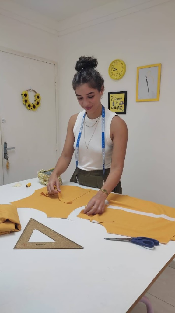 Aluna da Costuralle com fita métrica e modelagem sob medida cortada