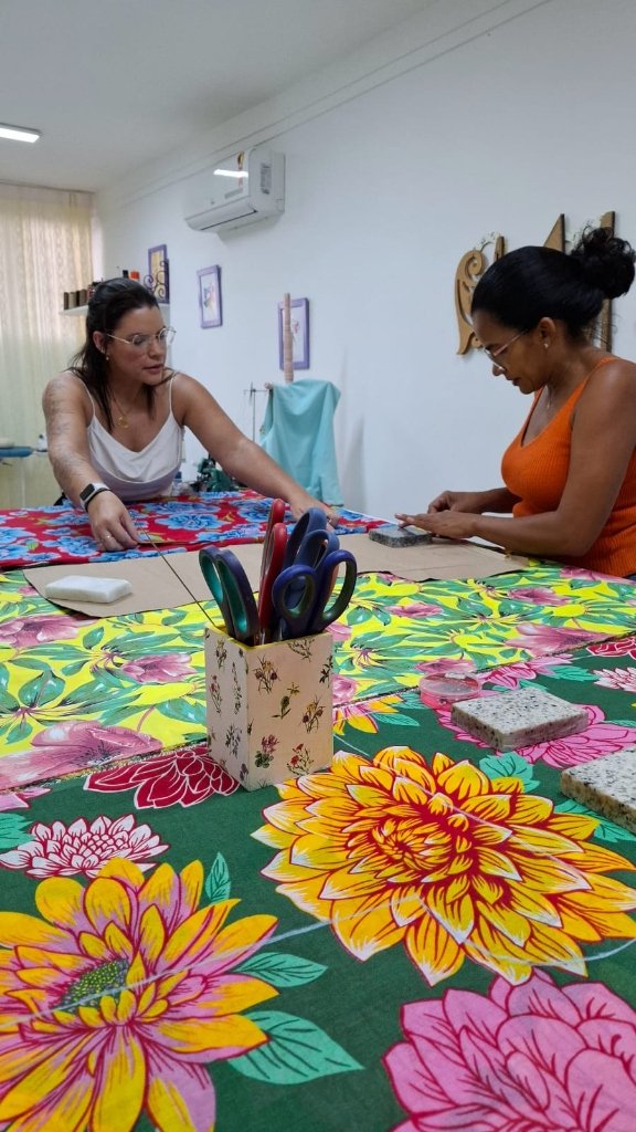 Alunas reunidas na bancada de corte e costura no ateliê Costuralle
